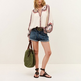 Model wearing Bash cream embroidered boho blouse with denim shorts, styled with green tote bag and black strappy sandals