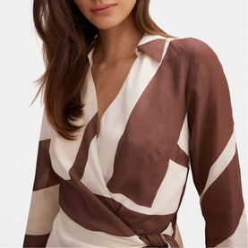 Model wearing Forever New Driftwood Geo wrap dress with V-neckline, long sleeves, and tie waist in brown and cream geometric print.