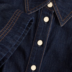 Phase Eight blue denim shirt dress close-up, showing contrast orange topstitching, point collar and ivory snap buttons