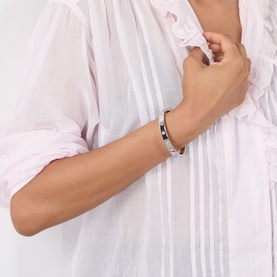 Model with Coach Hinge Bangle Bracelet in rhodium, silver-toned brass with cubic zirconia and logo detailing, hinge closure