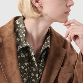 Model with small gold stud earring, styled with tan suede blazer and olive floral shirt