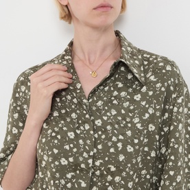 Model wearing khaki floral print shirt with classic collar, styled with a gold pendant necklace