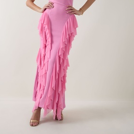 Model wearing Elliatt pink ruffle gown, styled with matching pink strappy heeled sandals, cropped view showing skirt detail.