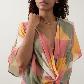 Model wearing Eres Nuance Printed Kaftan in multi colourway, close-up showing V-neckline twist detail and short sleeves, styled with gold chain