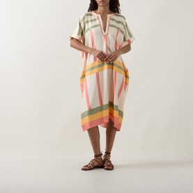 Model wearing Eres Multi silk cover-up dress in cream with pink, green and yellow stripe print, styled with tan strappy sandals