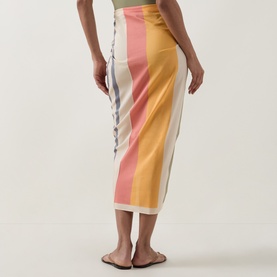 Model wearing Eres Croquant Printed Sarong in multi colourway block stripes, self-tie side fastening, styled with brown flat sandals