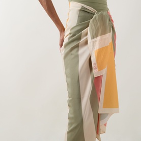Model wearing Eres Croquant Printed Sarong in multi, tied over sage green trousers, featuring block stripe pattern in pink, yellow and cream.