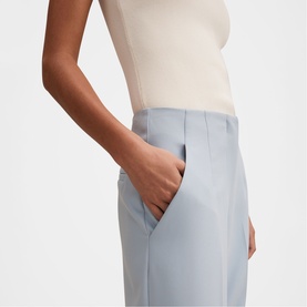 Model wearing Forever New sky blue tailored trousers with front pockets, styled with a cream sleeveless top.