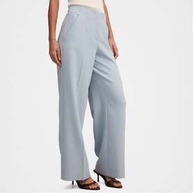 Model wearing Forever New sky blue wide-leg tailored trousers with high waist, styled with black heeled mules.