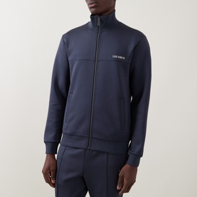 Model wearing Les Deux India Ink Blue casual zip-through jacket with ribbed cuffs and hem, styled with matching navy joggers.