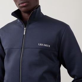 Model wearing Les Deux Casual Jacket in India Ink Blue, zip-through with funnel neck and embroidered logo on chest.