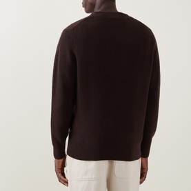 Model wearing Les Deux Mole Brown cotton crew neck knit, shown from the back, styled with cream trousers.