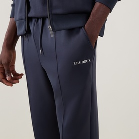 Model wearing Les Deux India Ink Blue sweatpants with zip pockets and embroidered logo, styled with matching hoodie