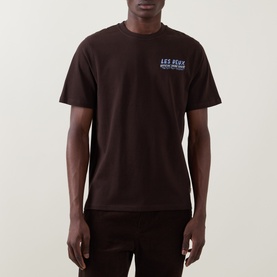 Model wearing Les Deux Record Logo Back Graphic T-Shirt in Mole Brown, crew neck, short sleeves, with blue chest logo graphic