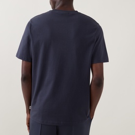 Model wearing Les Deux T-shirt in India Ink Blue, rear view, short sleeves, relaxed fit, 100% cotton