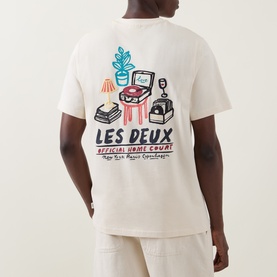 Model wearing Les Deux ivory cotton T-shirt, back view showing illustrated Home Court graphic print with record player and plants motif.