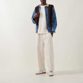Model wearing Les Deux ivory cotton T-shirt, styled with blue denim jacket, cream wide-leg trousers and white trainers.