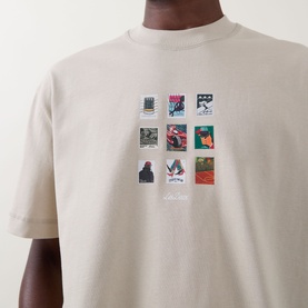 Model wearing Les Deux light sand cotton T-shirt with multicoloured postage stamp graphic print at chest