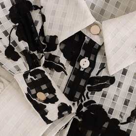 Phase Eight white check print dress, close-up of black ruffle trim detail and cream button fastening at collar