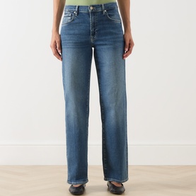 Model wearing Seven Jeans mid blue tapered denim jeans with slight fade detail, styled with a lime green top and dark flat shoes.