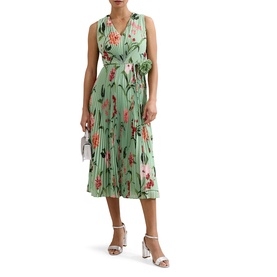 Model wearing green floral sleeveless midi dress with pleated skirt and tie waist, styled with white heeled sandals and silver clutch bag