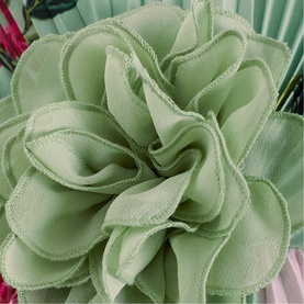 Close-up of a sage green layered fabric flower corsage brooch with ruffled petal edges