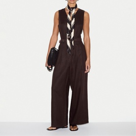 Model wearing Jigsaw cream silk scarf tied at neck, styled with dark brown wide-leg trousers, waistcoat, and black clutch bag