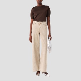 Model wearing Maje clear wide-leg jeans with frayed hem, styled with a dark brown short-sleeve knit top and white heeled mules.