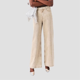 Model wearing Maje wide-leg clear wash jeans, styled with white heels and a white bag tucked into the waistband.