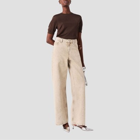 Model wearing Maje wide-leg clear jeans with dark brown short-sleeve top, styled with silver heels and carrying a metallic clutch bag