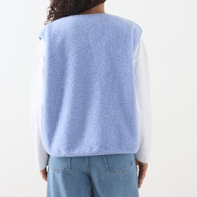Model wearing AMERICAN VINTAGE Hoktown Logo Gilet in Givre Chine blue fleece, back view, styled with white long-sleeve top and blue jeans