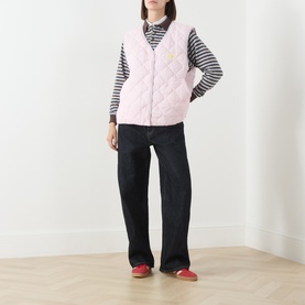 Model wearing American Vintage pink quilted gilet over striped long-sleeve top, styled with dark wide-leg jeans and red flats.