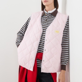 Model wearing American Vintage pink quilted gilet over striped long-sleeve top, styled with red wide-leg trousers