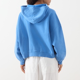 Model wearing American Vintage Plizzy Logo Hoodie in Nautique Vintage, rear view showing dropped shoulders and fixed hood, styled with white trousers.