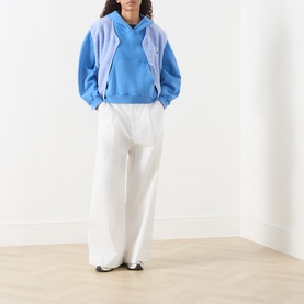 Model wearing American Vintage Plizzy Logo Hoodie in Nautique Vintage with white wide-leg trousers and black flats.