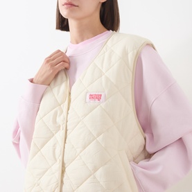 Model wearing American Vintage cream quilted gilet with logo patch, styled with a pink sweatshirt underneath.