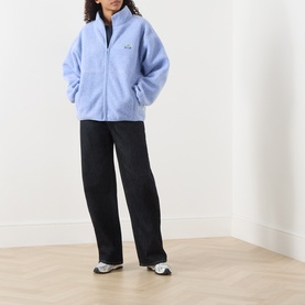Model wearing American Vintage Hoktown Logo Fleece Jacket in Givre Chine with black wide-leg trousers and white trainers