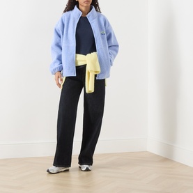 Model wearing American Vintage Hoktown Logo Fleece Jacket in Givre Chine, styled with black wide-leg trousers and a yellow tied sweatshirt