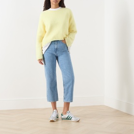 Model wearing American Vintage Joybird Cropped Straight-Leg Jeans in Authentique Stone, styled with a yellow crew-neck jumper and green trainers