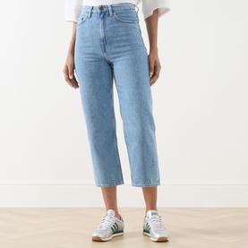 Model wearing American Vintage Joybird Cropped Straight-Leg Jeans in Authentique Stone light wash denim, styled with white tee and green trainers.