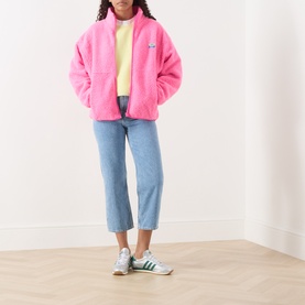 Model wearing American Vintage Joybird Cropped Straight-Leg Jeans in Authentique Stone, styled with pink fleece jacket and green trainers