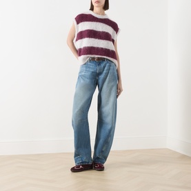 Model wearing American Vintage knit vest in rayures cranberry stripe, styled with light blue wide-leg jeans and burgundy loafers.