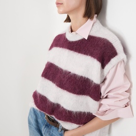 Model wearing American Vintage knitwear vest in rayures cranberry stripe, fluffy alpaca blend, styled over pink shirt with jeans.