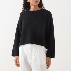 Model wearing American Vintage Vitow Knitted Sweater in black with boat neckline and ribbed trims, styled with white trousers