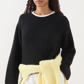 Model wearing American Vintage Vitow Knitted Sweater in black with boat neckline, styled with a yellow jumper tied at the waist.