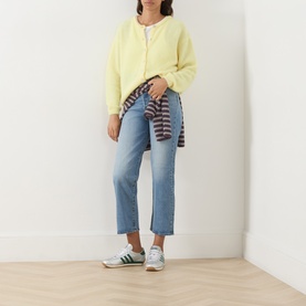 Model wearing American Vintage citronnier chin&eacute; knit cardigan with light blue jeans and green trainers, striped top tied at waist.