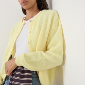 Model wearing American Vintage cardigan in Citronnier Chine, styled with a white tee and striped trousers. Round neck, button-front knit.