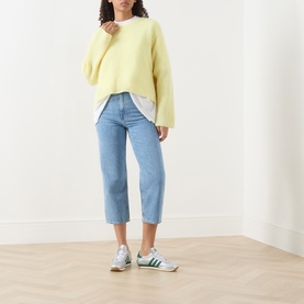 Model wearing American Vintage Vitow Knitted Sweater in Citronnier Chine, styled with light blue cropped jeans and green trainers