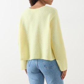 Model wearing American Vintage Vitow Knitted Sweater in Citronnier Chine, back view, with light blue jeans. Soft cropped silhouette, long sleeves.