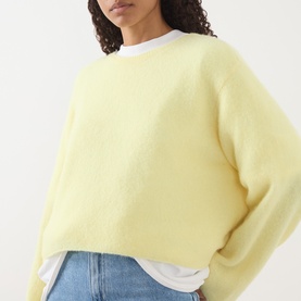 Model wearing American Vintage Vitow Knitted Sweater in Citronnier Chine, styled over a white tee with blue jeans